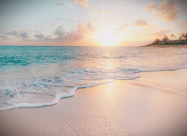 Tropical beach at sunset with turquoise water and gentle foam on tan sand